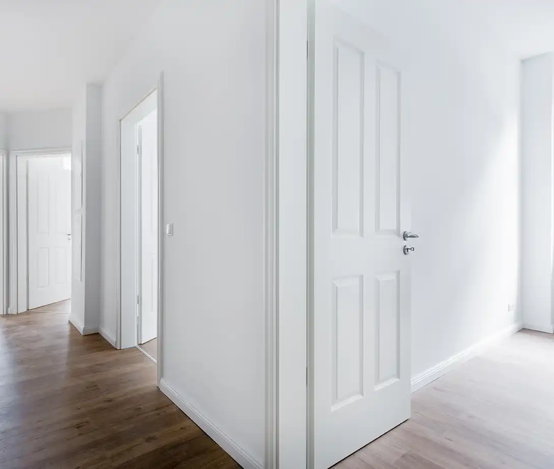 Heller Wohnungsflur mit mehreren weißen Innentüren und Holzboden